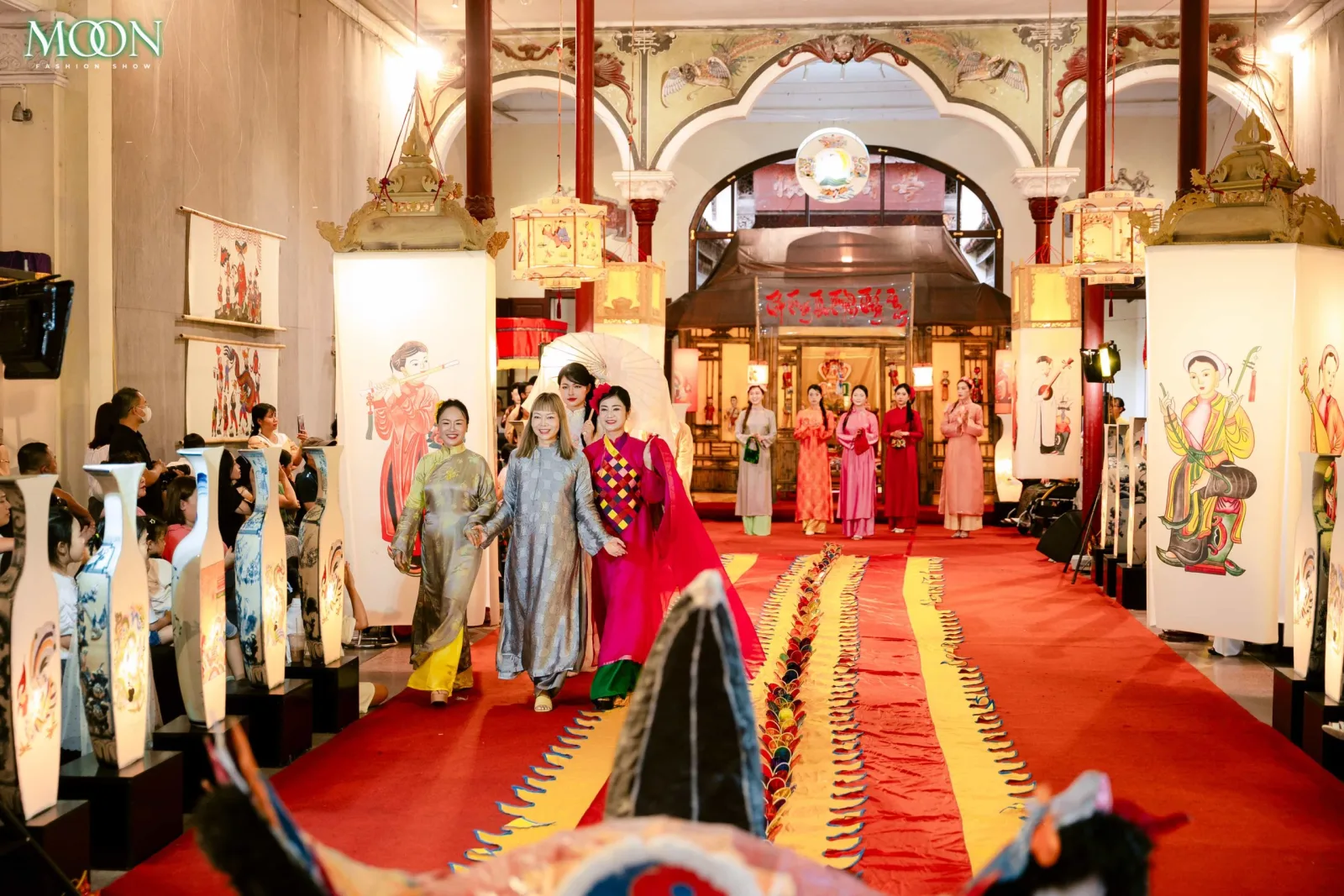 Models in traditional Vietnamese attire walk the runway during the Moon Fashion Show 2025 in a cultural setting.