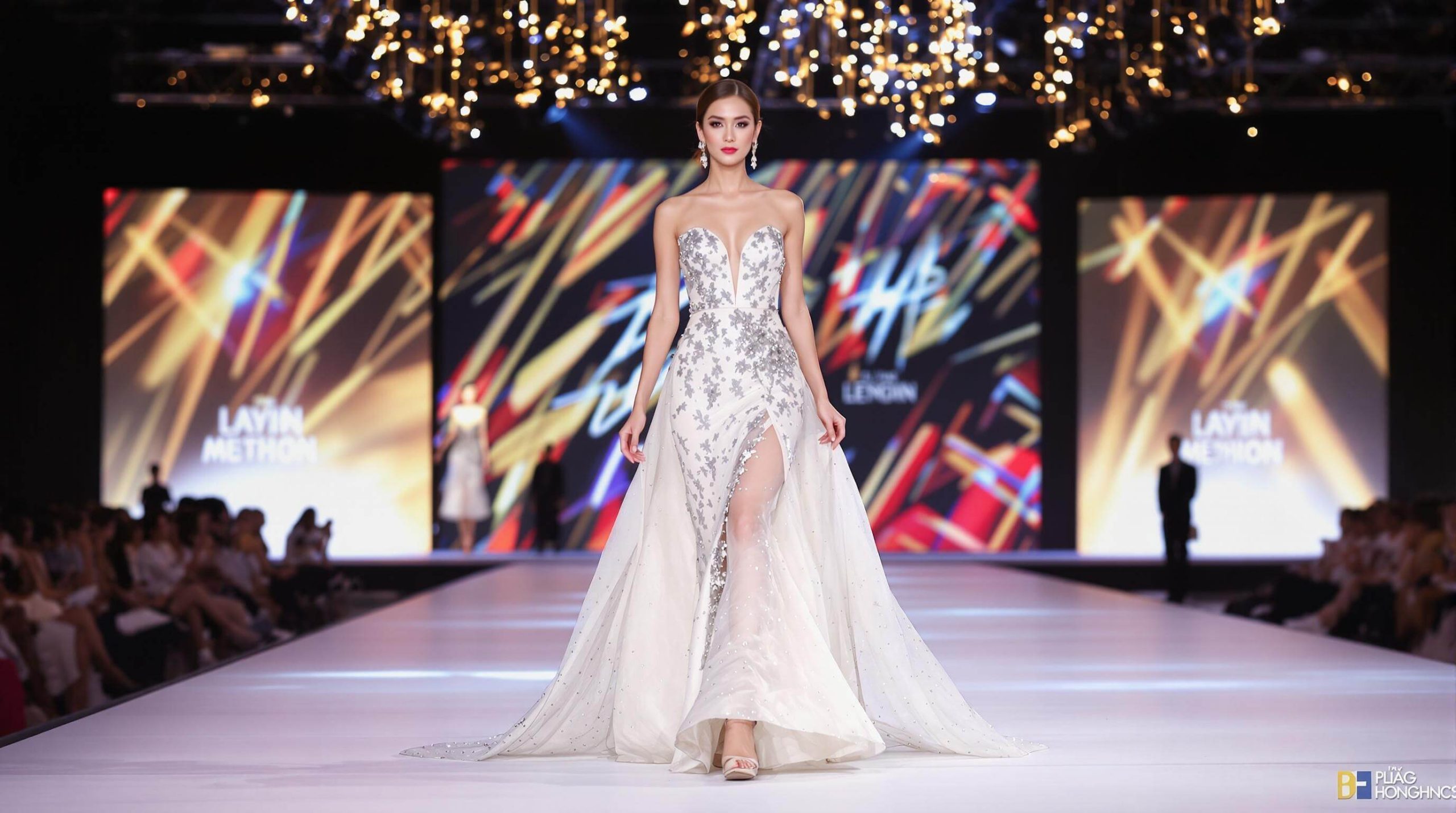 Full body shot of a Vietnamese female model with thần thái sàn diễn cuốn hút, walking confidently on a fashion runway under bright lights.
